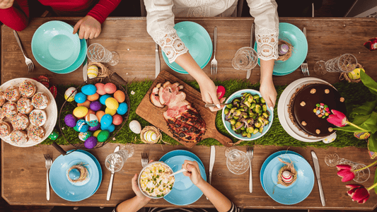 Table de Pâques joliment décorée avec des plats savoureux et colorés, des oeufs de Pâques colorés et des fleurs printanières.